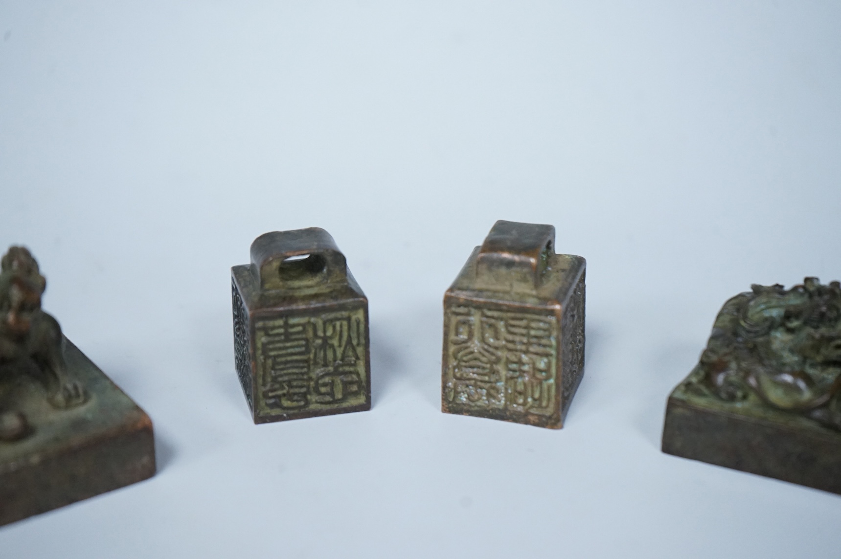 Four Chinese bronze seals, one in the form of two lion dogs, largest 7.5cm wide